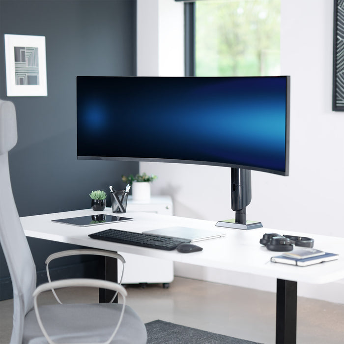 Modern office desk with a large monitor, keyboard, and chair.