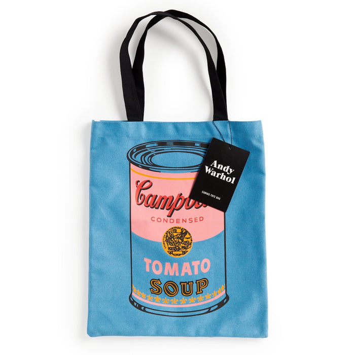 The Warhol Soup Can Volume 3 Canvas Tote Bag by the Andy Warhol Foundation features a blue design with the iconic Campbell’s Tomato Soup can, black handles, and a tag reading “Andy Warhol.”.