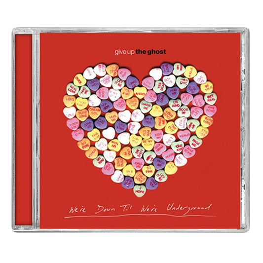 The Give Up The Ghost CD cover shows candy hearts in a heart shape on a red background, with the handwritten album title “We’re Down Til We’re Underground” at the bottom, echoing the hardcore scene vibe.