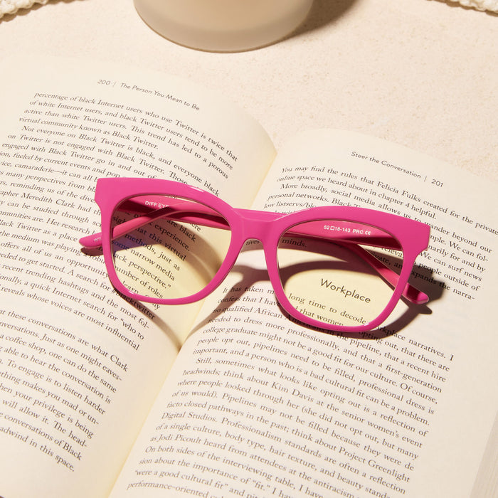 still life of the diff eyewear willa square prescription glasses with a bubble gum pink acetate frame laying on a open book
