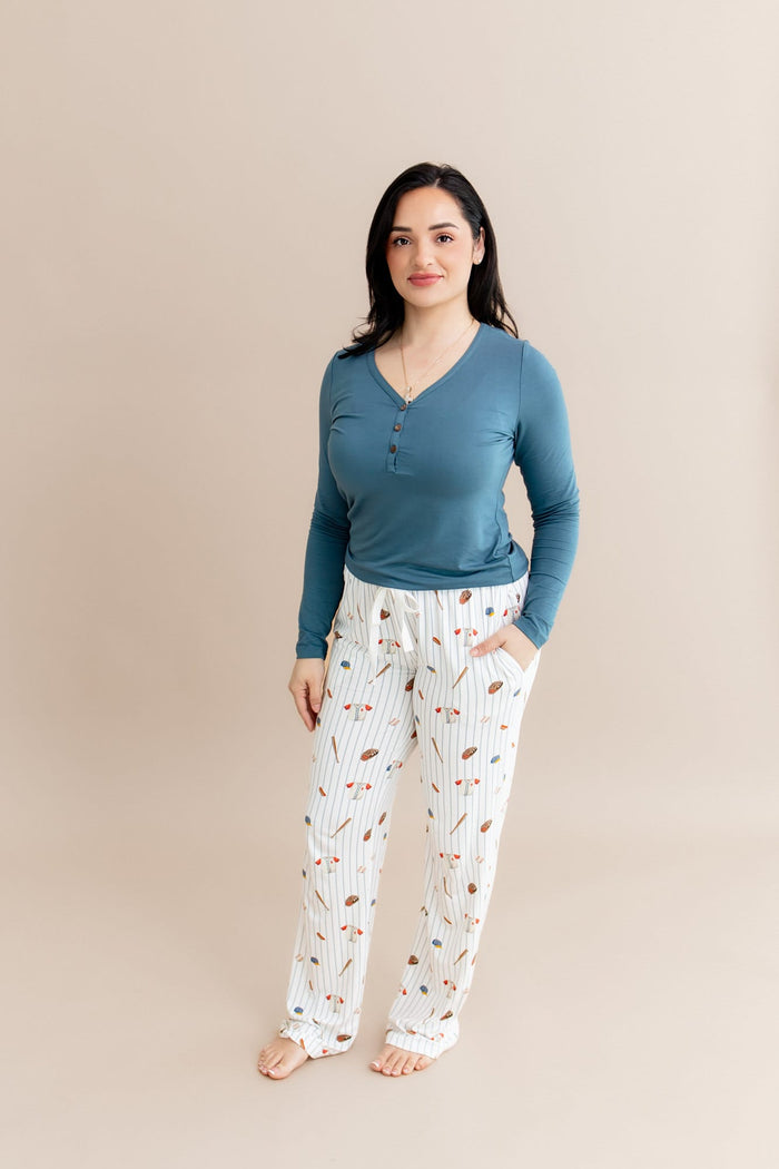 Female posing earing the Women's Lounge Pants in Home Run paired with a muted blue long sleeve henley