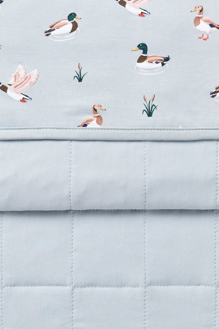 Close up of the Youth Blanket in Mallard Duck 1.0 showing the light blue quilted backing and patterned smooth top layer