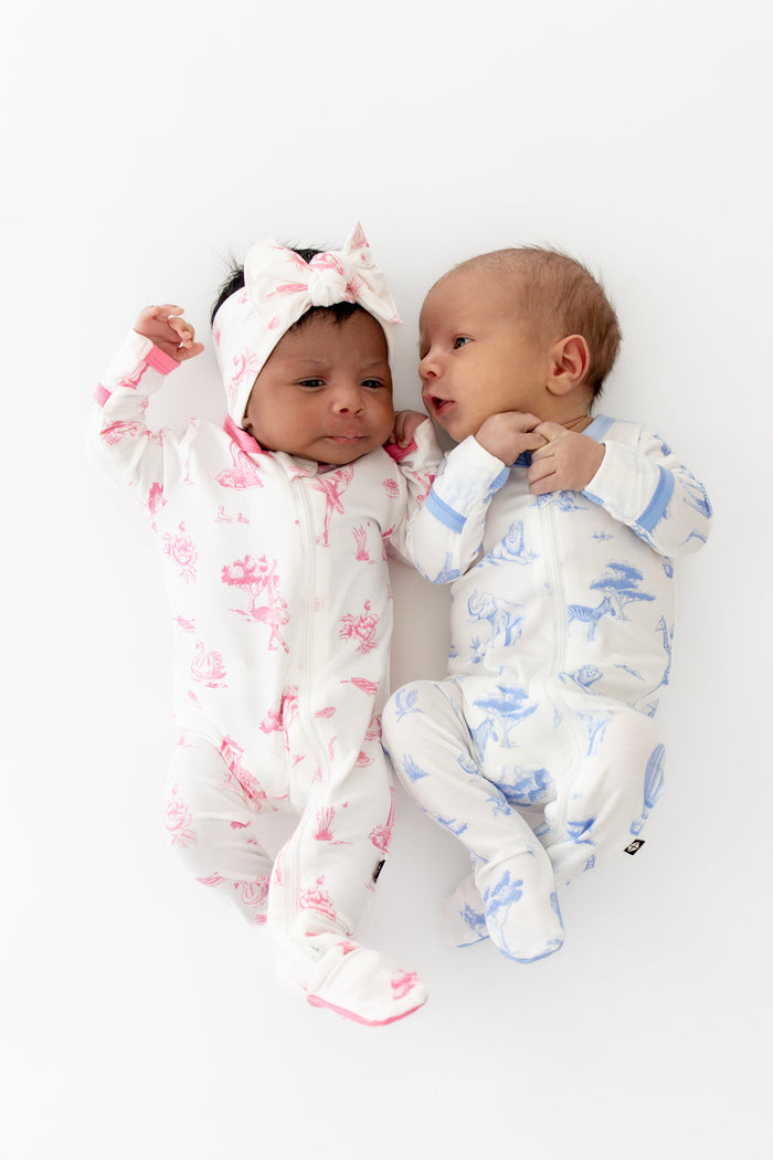 Two babies in colorful toile footed pajamas on a white background